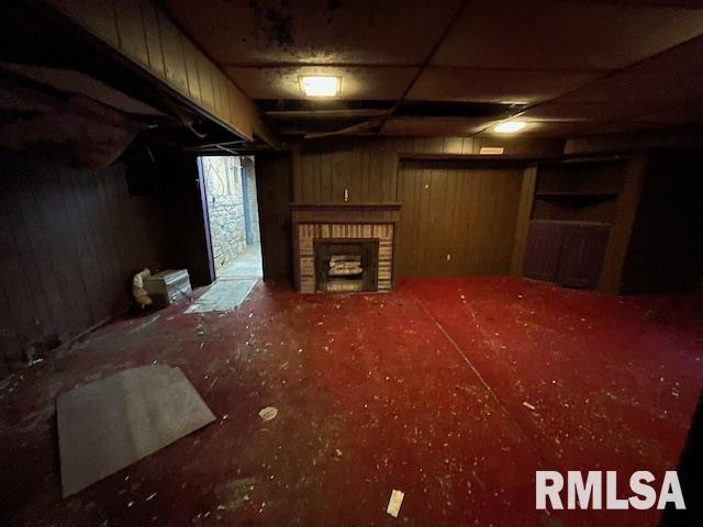 704 S Lafayette St, Macomb, IL 61455 - unfurnished living room featuring a fireplace and wood walls