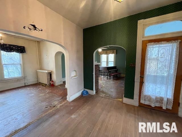 foyer entrance with hardwood / wood-style floors and radiator heating unit