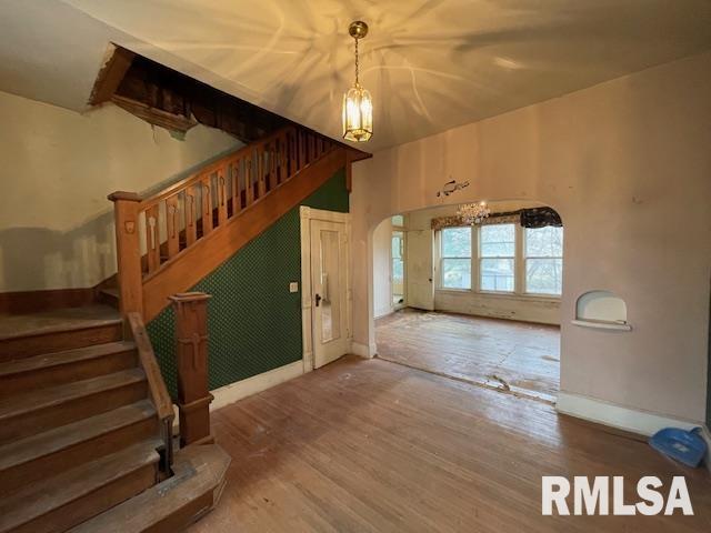 704 S Lafayette St, Macomb, IL 61455 - entryway featuring wood finished floors, arched walkways, stairway, baseboards, and a chandelier