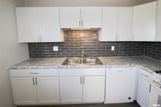 kitchen with white appliances, backsplash, sink, light stone countertops, and white cabinetry