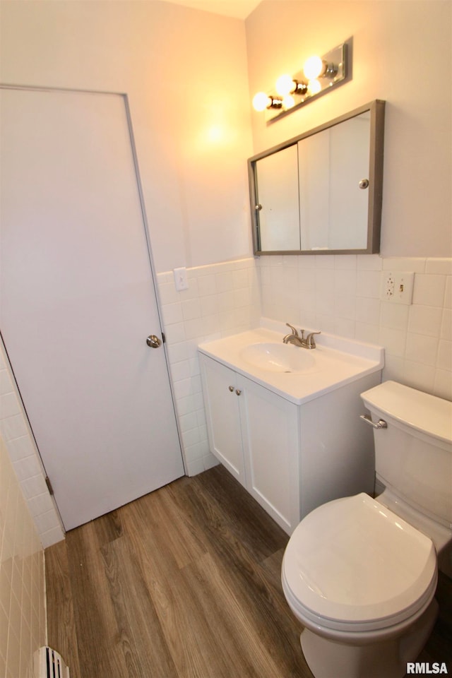 bathroom with hardwood / wood-style floors, vanity, toilet, and tile walls