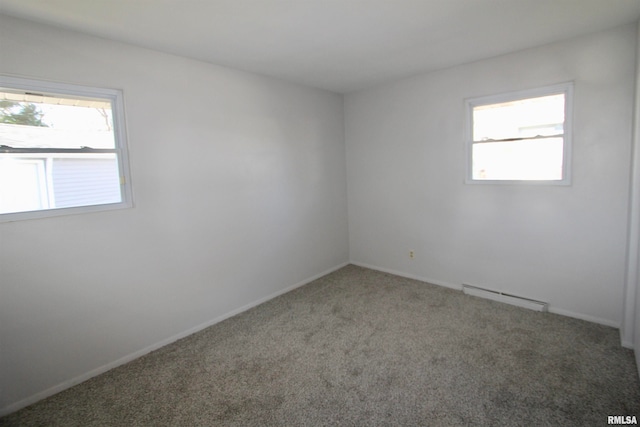 carpeted spare room with a baseboard heating unit