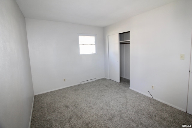 unfurnished bedroom featuring carpet flooring, a closet, and baseboard heating