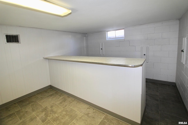 interior space featuring kitchen peninsula, wooden walls, and white cabinets