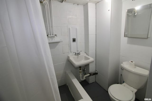 bathroom with toilet and tile walls