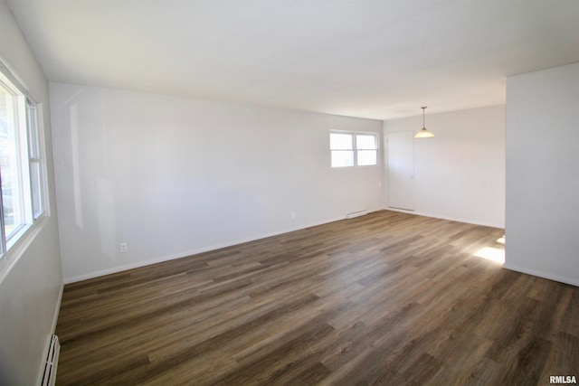 spare room featuring baseboard heating and dark wood-type flooring