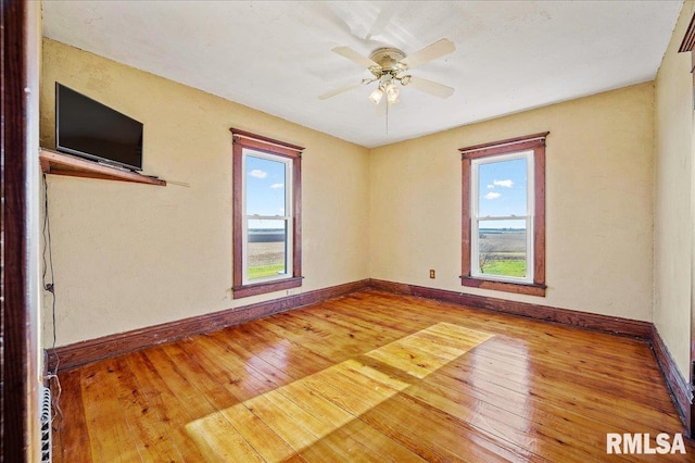 spare room with hardwood / wood-style flooring, a wealth of natural light, and ceiling fan