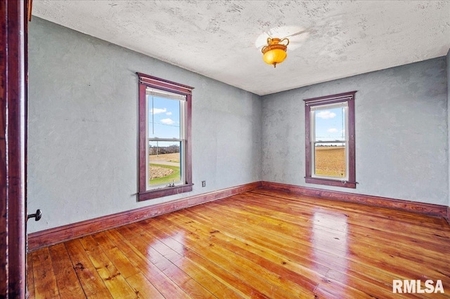 empty room featuring hardwood / wood-style flooring, a textured ceiling, and a wealth of natural light