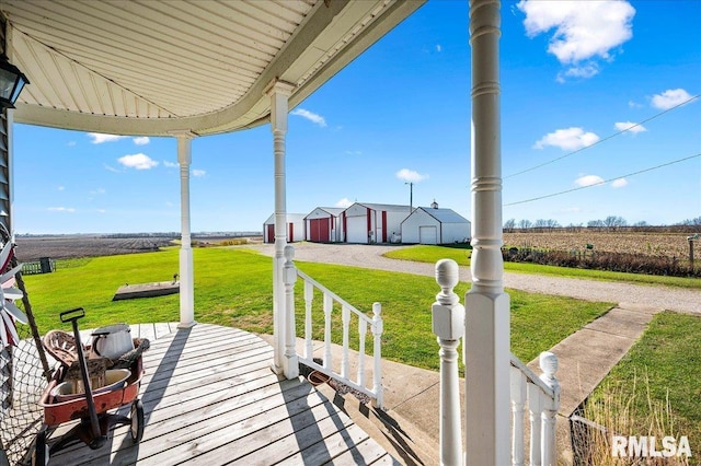 exterior space featuring a rural view, a yard, a garage, and covered porch