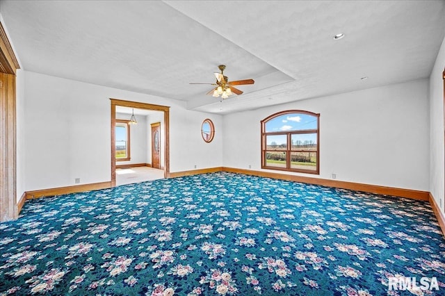 unfurnished room with a raised ceiling, carpet, and ceiling fan