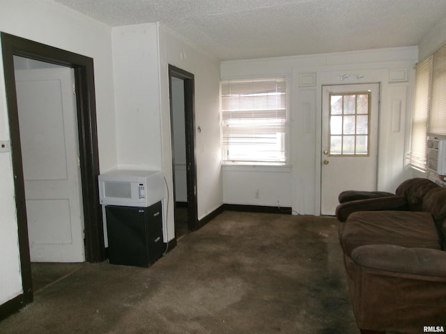 living room with cooling unit, a textured ceiling, and dark colored carpet