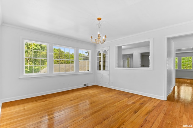 empty room featuring light hardwood / wood-style flooring, a notable chandelier, and crown molding