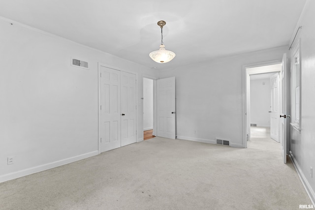 unfurnished bedroom with crown molding, a closet, and light colored carpet