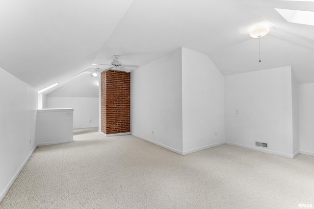 bonus room with ceiling fan, lofted ceiling with skylight, and light carpet