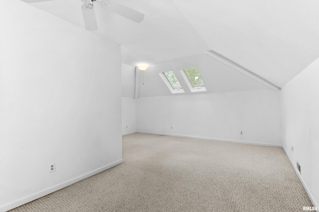 additional living space featuring ceiling fan, lofted ceiling with skylight, and light carpet