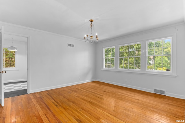 unfurnished room featuring crown molding, plenty of natural light, a notable chandelier, and light wood-type flooring