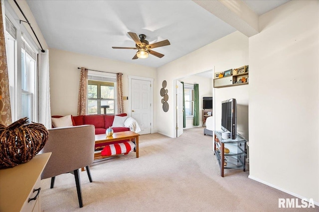 living room featuring beamed ceiling, ceiling fan, and light carpet