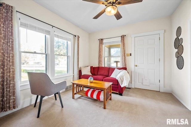 living area featuring light carpet, plenty of natural light, and ceiling fan