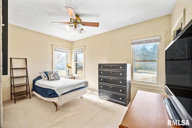 bedroom with ceiling fan, light carpet, and multiple windows