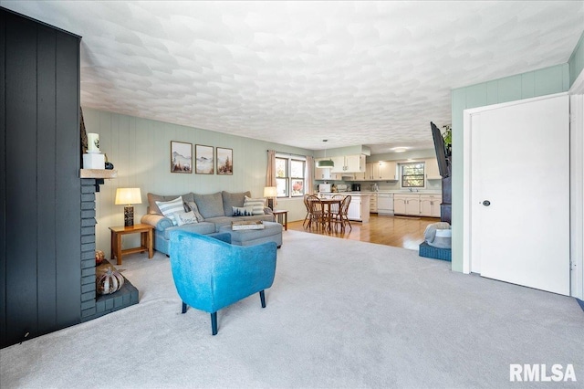 carpeted living room featuring a textured ceiling and a brick fireplace