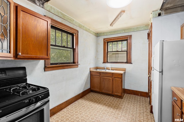 kitchen with sink, white fridge, and stainless steel range with gas stovetop