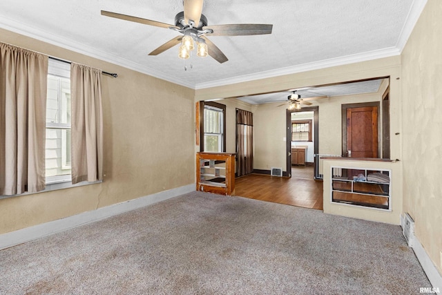 unfurnished living room with a textured ceiling, ceiling fan, crown molding, and dark carpet