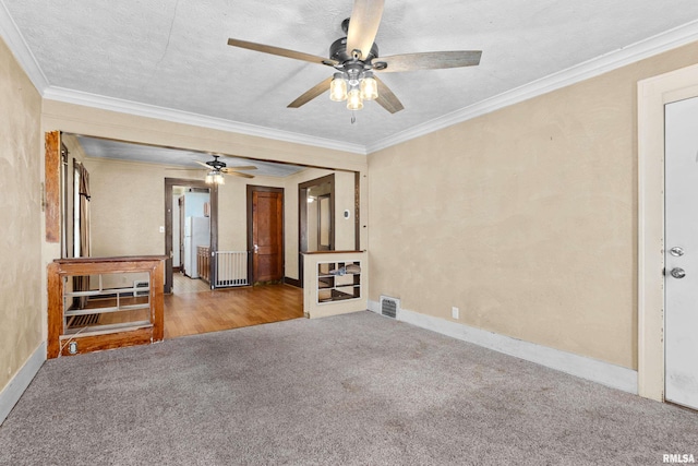 empty room with light carpet, ceiling fan, ornamental molding, and a textured ceiling