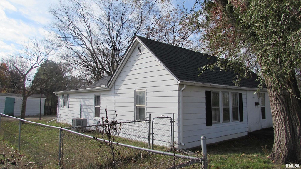 view of side of home with roof with shingles and fence