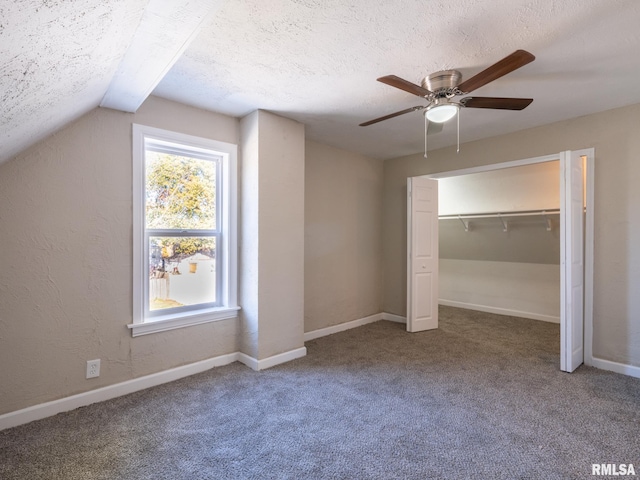 unfurnished bedroom with carpet flooring, a textured ceiling, ceiling fan, a closet, and lofted ceiling