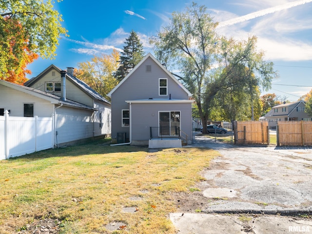 rear view of property with cooling unit and a yard