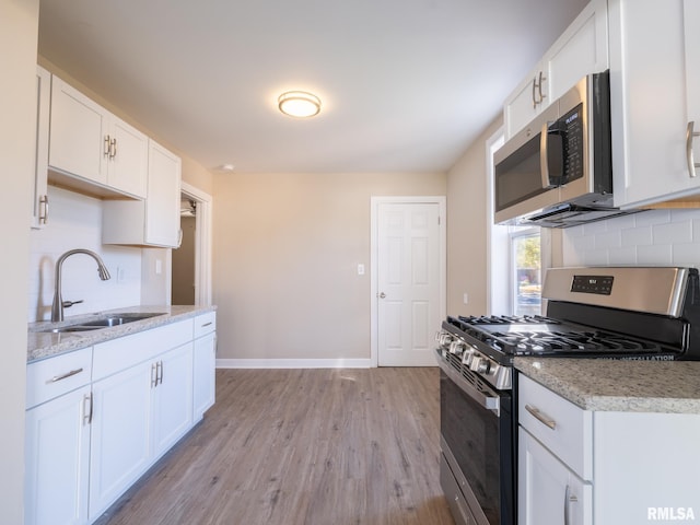 kitchen featuring white cabinetry, sink, light hardwood / wood-style flooring, and appliances with stainless steel finishes