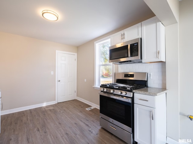 kitchen featuring light stone counters, appliances with stainless steel finishes, decorative backsplash, white cabinets, and light wood-type flooring