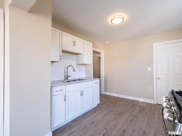 kitchen with white cabinets, sink, light hardwood / wood-style flooring, stainless steel gas stove, and light stone countertops