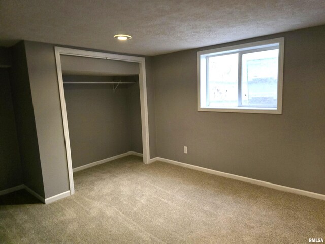 unfurnished bedroom featuring carpet, a textured ceiling, and a closet