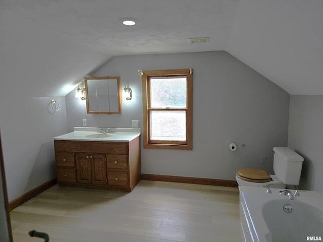 bathroom featuring hardwood / wood-style flooring, vanity, vaulted ceiling, and toilet