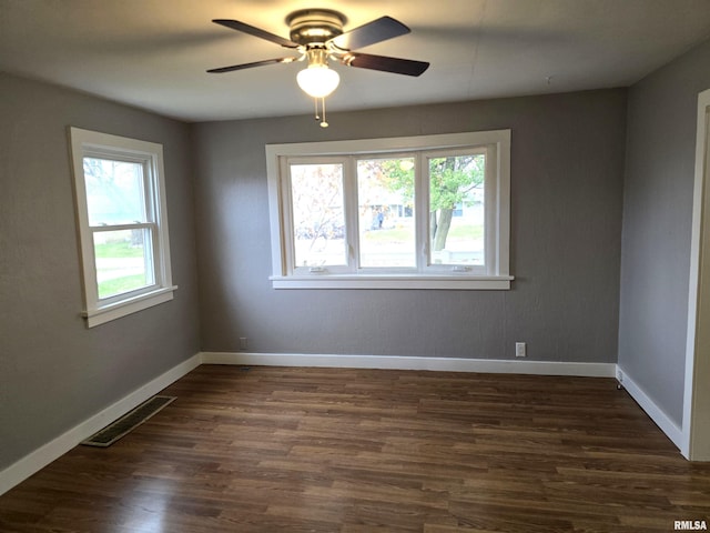 empty room featuring a wealth of natural light, dark wood-type flooring, and ceiling fan