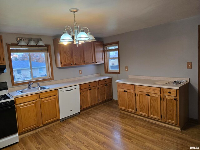 kitchen with sink, white appliances, hanging light fixtures, and a wealth of natural light