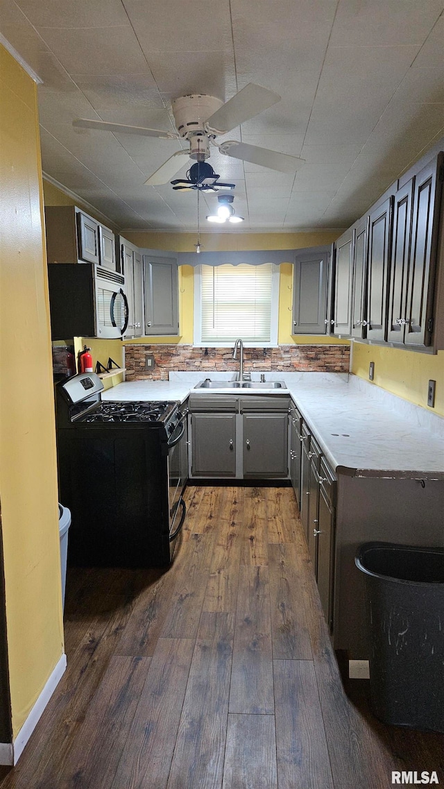 kitchen featuring black gas range, decorative backsplash, sink, and dark wood-type flooring