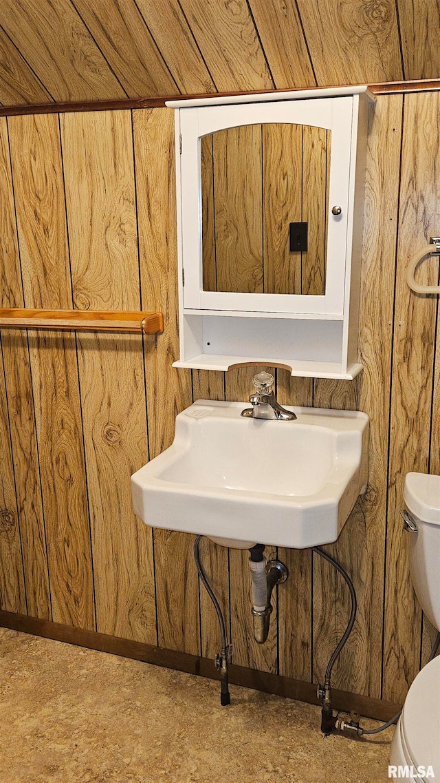 bathroom with toilet and wood walls