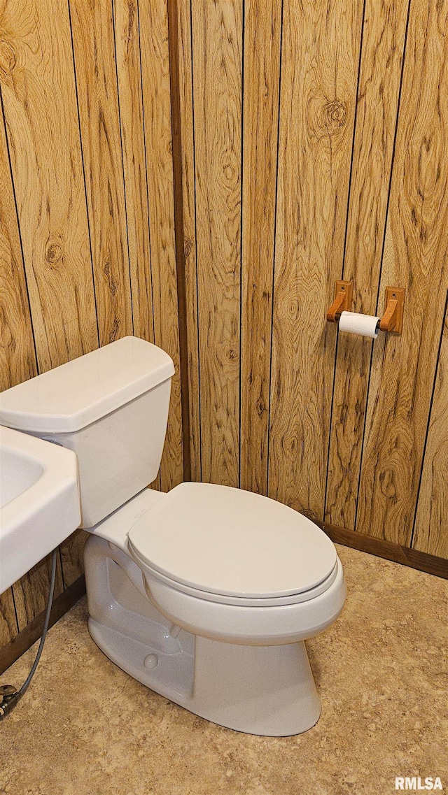 bathroom featuring wood walls and toilet