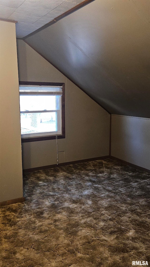 bonus room featuring dark carpet and vaulted ceiling