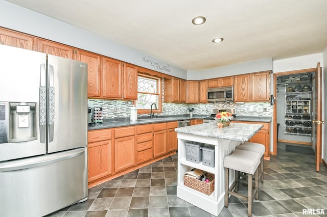 kitchen featuring a kitchen bar, backsplash, stainless steel appliances, sink, and a kitchen island