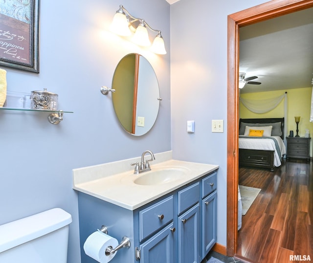 bathroom featuring ceiling fan, toilet, vanity, and hardwood / wood-style flooring