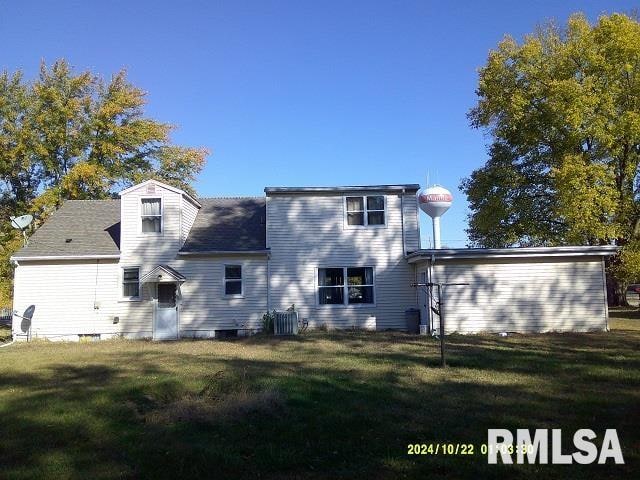 rear view of property featuring central AC and a lawn