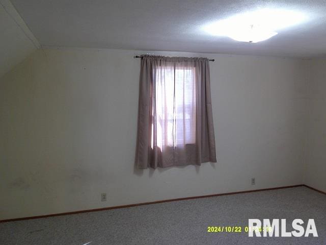 carpeted spare room featuring vaulted ceiling