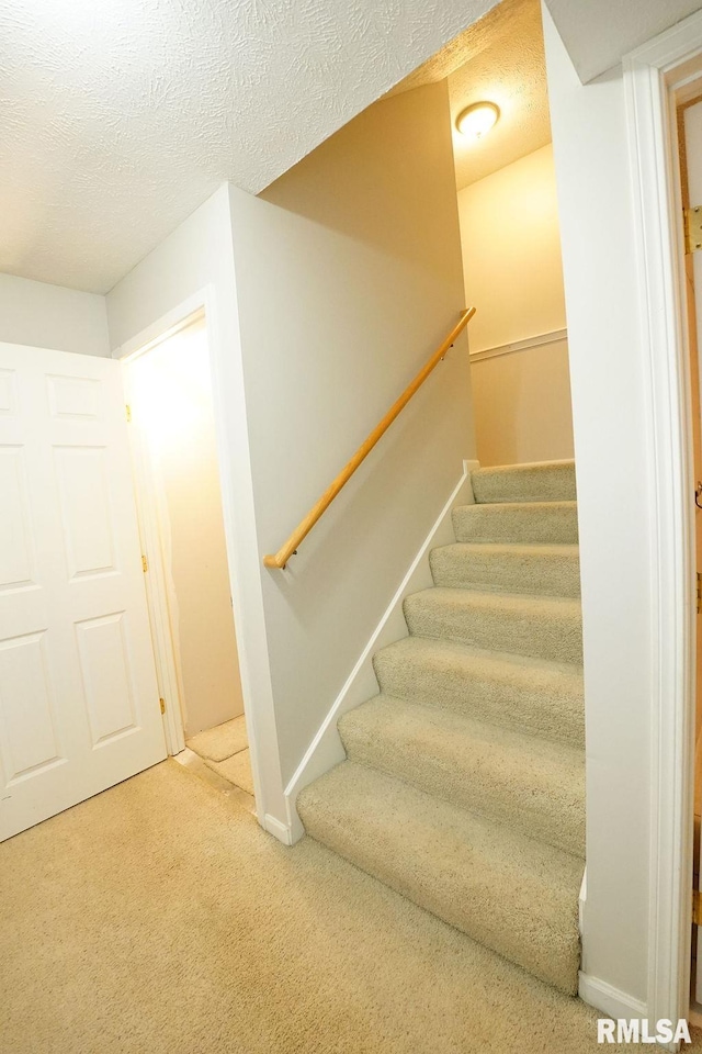 stairs featuring carpet and a textured ceiling