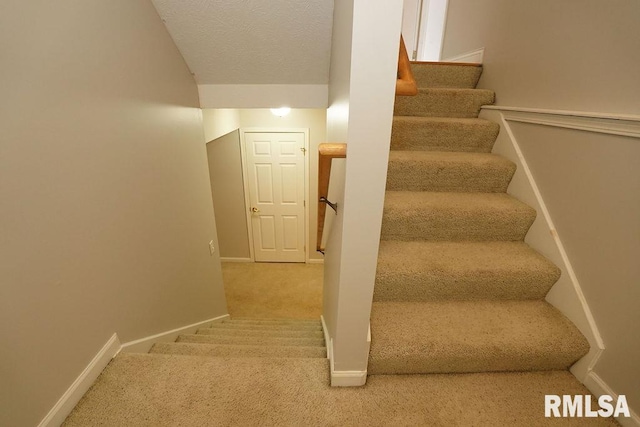 staircase with carpet and a textured ceiling