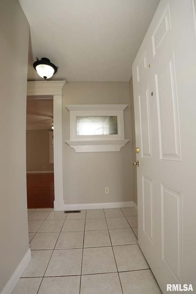 hall with a textured ceiling and light tile patterned flooring