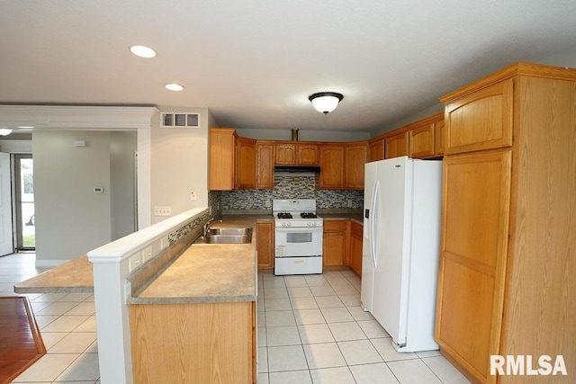 kitchen with decorative backsplash, kitchen peninsula, white appliances, sink, and light tile patterned floors