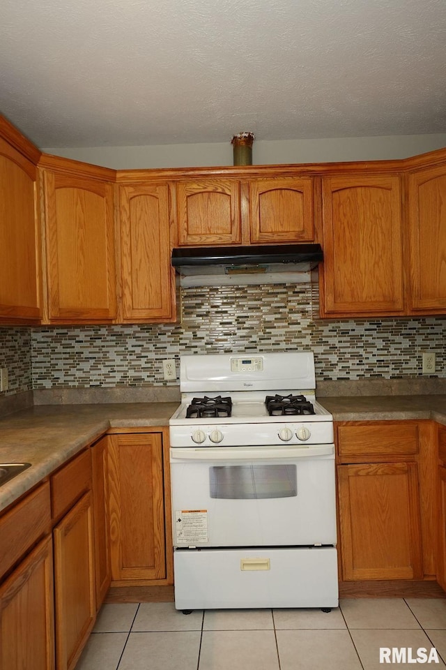 kitchen with white range with gas stovetop, backsplash, and light tile patterned floors